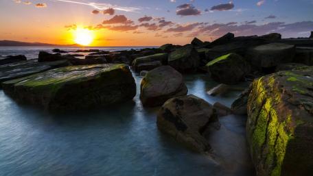 Serene Sunset Over Rocky Shoreline wallpaper