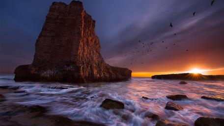 Majestic Sunset Over Rocky Shoreline wallpaper