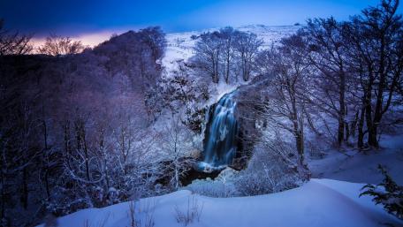 Majestic Winter Waterfall in a Snowy Landscape wallpaper