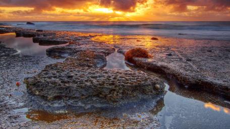 Serene Sunset Over Rocky Shoreline wallpaper
