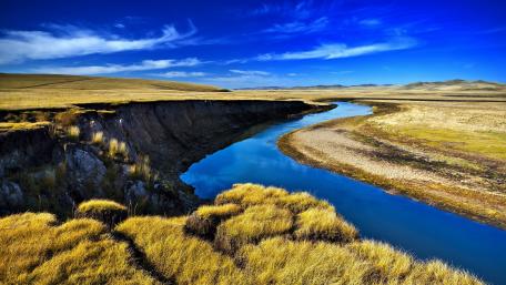 Serene River Flowing Through Golden Plains wallpaper