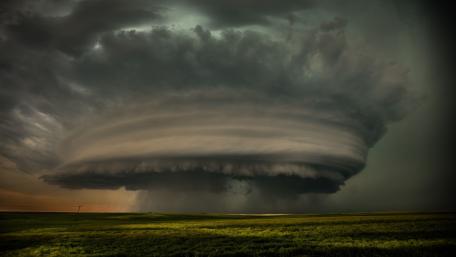 Majestic Whirlwind Over Rolling Fields wallpaper
