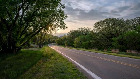Winding Road Through Lush Greenery and Clouds wallpaper