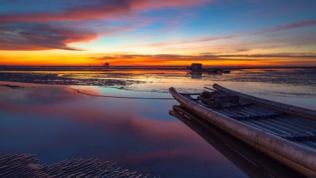Serene Sunset Over Calm Waters with Boat wallpaper