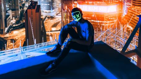 Masked man sitting on the top of building wallpaper