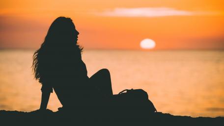 Sad girl by the beach at sunset wallpaper