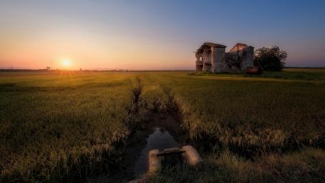 Sunset Over Abandoned House in Rural Fields wallpaper