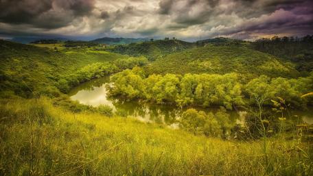 Serene River Flowing Through Lush Green Hills wallpaper