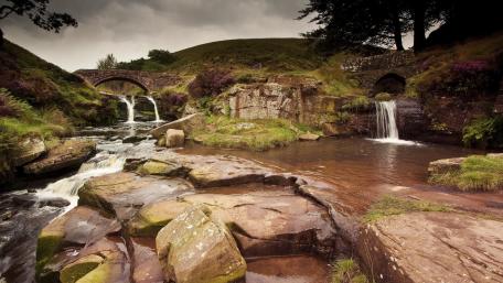 Serene River and Stone Bridge in Nature's Embrace wallpaper