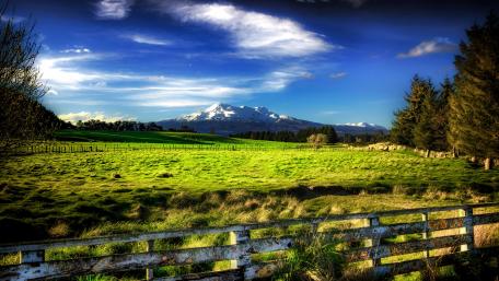 Majestic Mountain Landscape with Rolling Green Fields wallpaper
