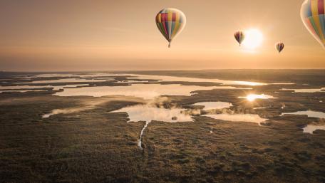 Colorful Balloons at Sunrise Over Scenic Landscape wallpaper