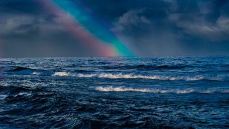 Majestic Rainbow Over Dark Ocean Waves wallpaper