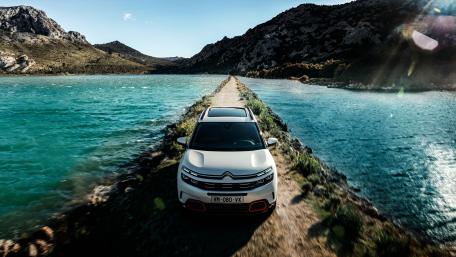 Sleek Car on Scenic Waterway Roadway wallpaper