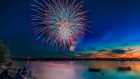 Vibrant Fireworks Over a Serene Lake Scene wallpaper