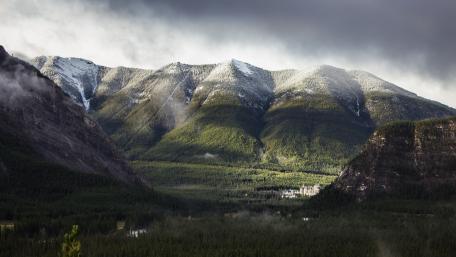 Majestic Mountain Valley Under Cloudy Skies wallpaper