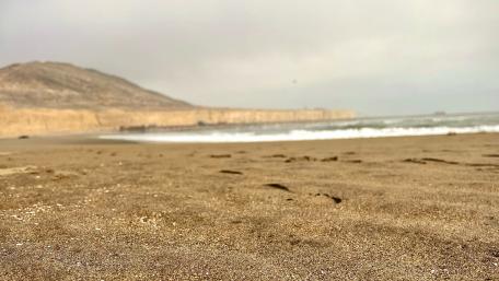 Serene Beach Scene with Gentle Waves and Rocky Cliffs wallpaper