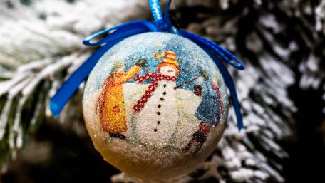 Joyful Christmas Decorated Ball Hanging from a Snowy Tree wallpaper