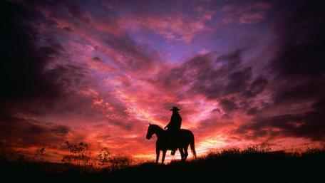 Cowboy Silhouette Against a Vivid Sunset Sky wallpaper