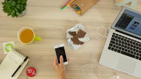 Indulgent Workspace with Chocolate Treats and Gadgets wallpaper