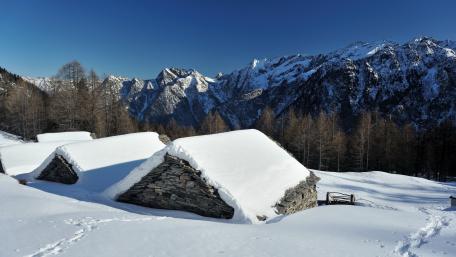 Cozy Winter Cottage Amidst Majestic Mountains wallpaper