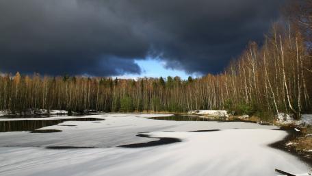Serene Winter Landscape with Frozen Lake and Dark Clouds wallpaper