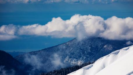 Majestic Mountains Amidst Fluffy Clouds wallpaper