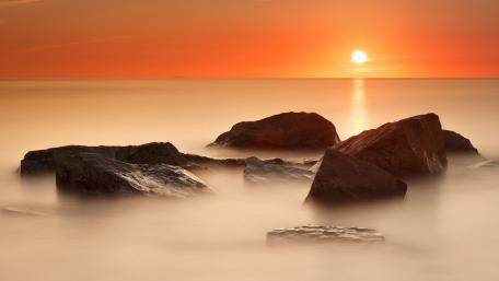 Serene Orange Sunset Over Tranquil Sea wallpaper