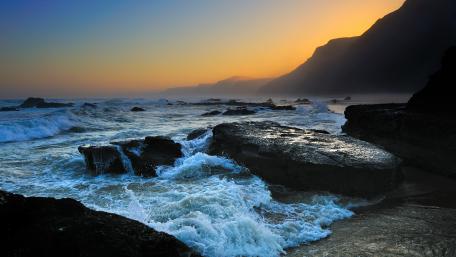 Serene Coastal Sunset Over Rugged Rocks wallpaper
