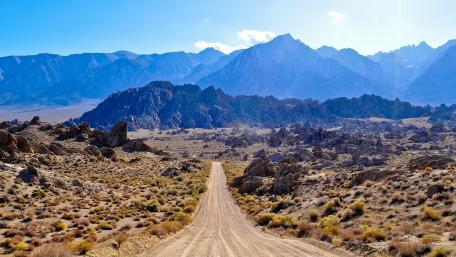 Scenic Desert Road Surrounded by Majestic Mountains wallpaper