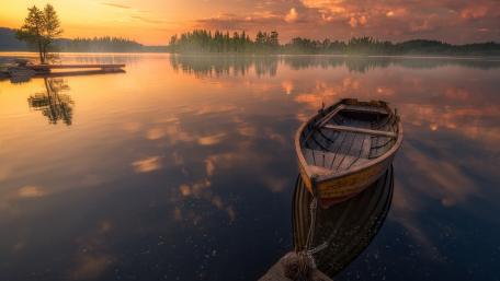 Tranquil Lake at Sunset with Boat Reflection wallpaper