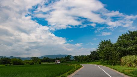 Tranquil Country Road among Lush Fields and Blue Skies wallpaper