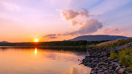 Serene Sunset Over Tranquil Waters and Forested Hills wallpaper