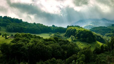 Serene Mountain Retreat Under Dramatic Clouds wallpaper