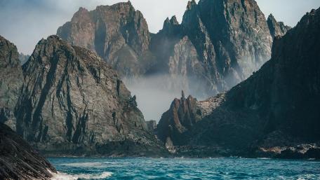 Majestic Cliffside Mountains Under Misty Skies wallpaper