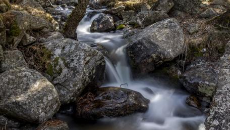 Serene Creek Flowing Through Rocky Landscape wallpaper
