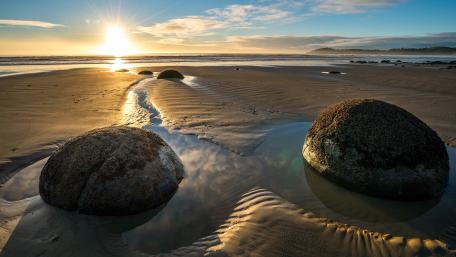 Golden Sunset Over Serene Beach Rocks wallpaper