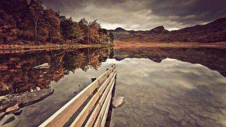 Serene Lake Reflection under Dark Clouds wallpaper