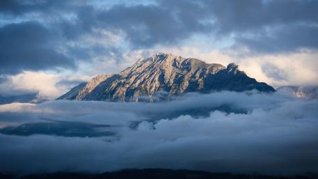 Majestic Alpine Peaks Emerging from Clouds wallpaper