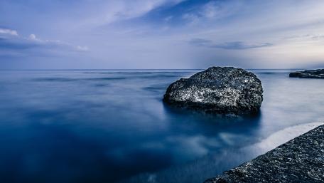 Serene Blue Sea with Boulder in Focus wallpaper