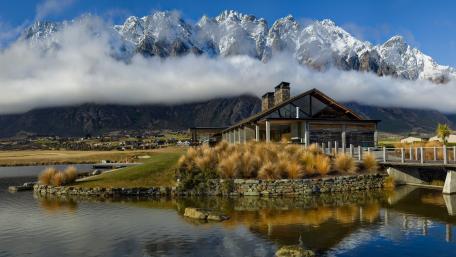 Serene Lakeside Cottage Amidst Majestic Mountains wallpaper