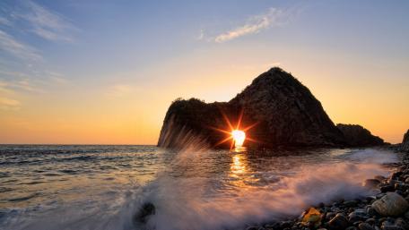 Breathtaking Sunrise Through Natural Arch Over Ocean Waves wallpaper