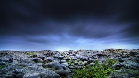 Ethereal Landscape of Mossy Terrain Under Darkening Skies wallpaper