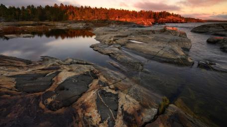 Serene Evening Reflection on Rocky Shoreline wallpaper