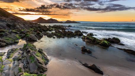 Serene Coastal Sunset Over Rocky Beachscape wallpaper
