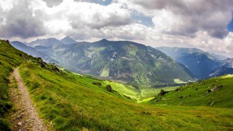 Serene Mountain Landscape with Lush Greenery and Rolling Clouds wallpaper