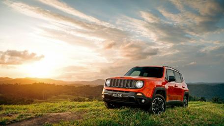 Vibrant Sunset with a Jeep on Scenic Terrain wallpaper