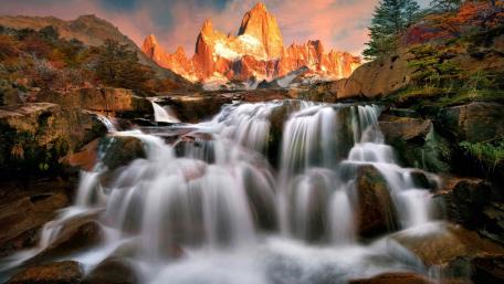 Majestic Waterfall Near Towering Mountains wallpaper