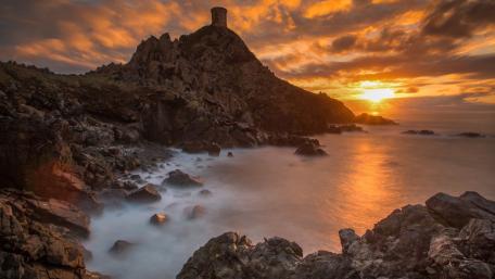 Majestic Sunset Over Rocky Coastline with Tower wallpaper
