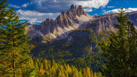 Majestic Mountain Peaks Surrounded by Lush Forests and Blue Skies wallpaper