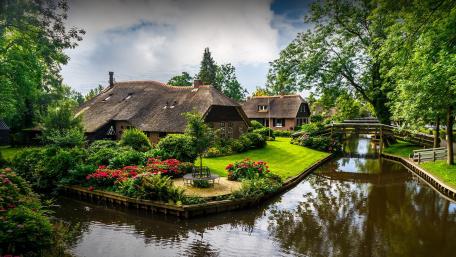 Charming Riverside Village with Lush Greenery and Tranquil Waters wallpaper